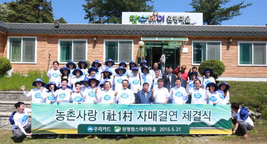 유구현 우리카드 대표(첫째줄 가운데)를 비롯한 임직원들이 21일 강원도 춘천시 사북면 원평팜스테이마을과 일사일촌 자매결연을 맺고 기념촬영을 하고 있는 모습.